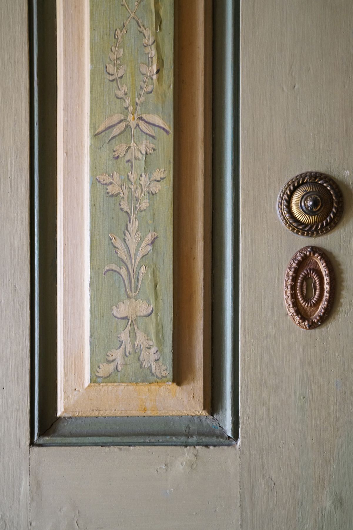 Detalhe do Palácio do Grilo em Lisboa, exibindo ornamentos esculpidos e ferragens antigas sobre madeira pintada, realçando a decoração histórica.