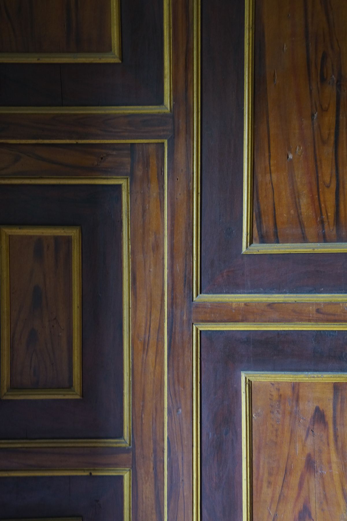 Detalhamento de painéis de madeira escura com molduras douradas, um elemento decorativo no Palácio do Grilo, Lisboa.