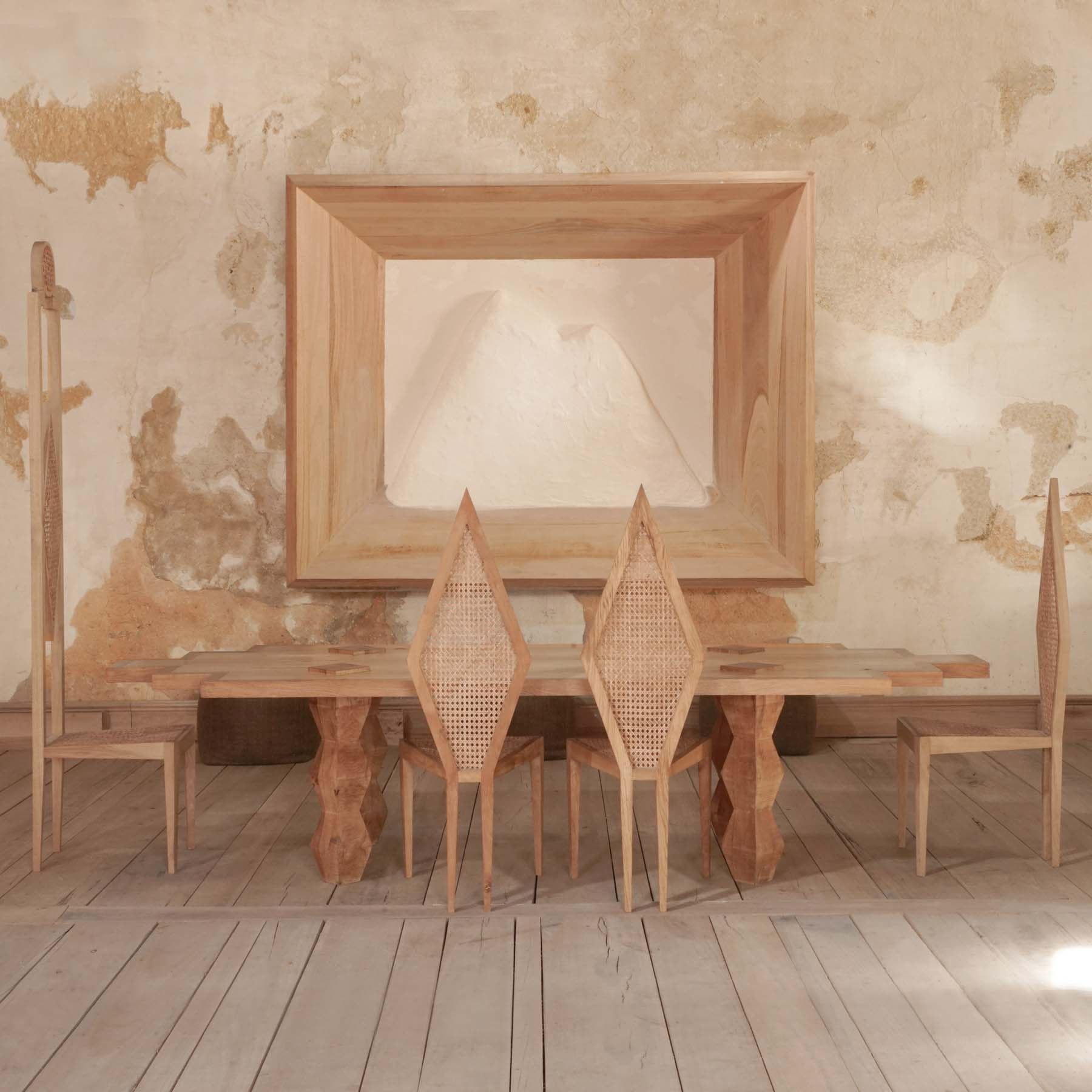 Mesa de jantar e cadeiras de madeira crua com encostos de ráfia, numa sala histórica do Palácio do Grilo, Lisboa.