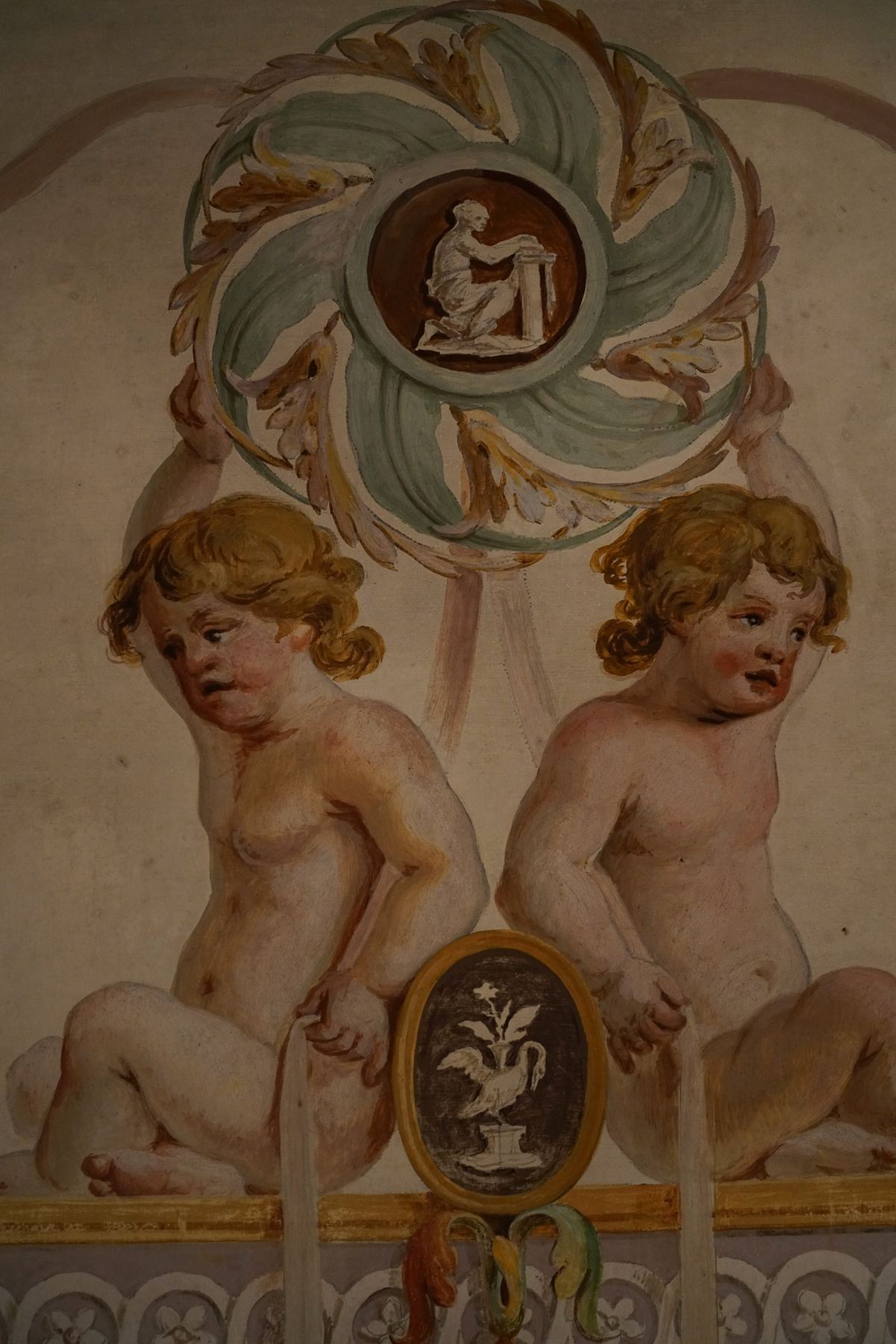 Pintura barroca no Palácio do Grilo em Lisboa, mostrando dois querubins gordinhos e detalhes ornamentais coloridos na parede.