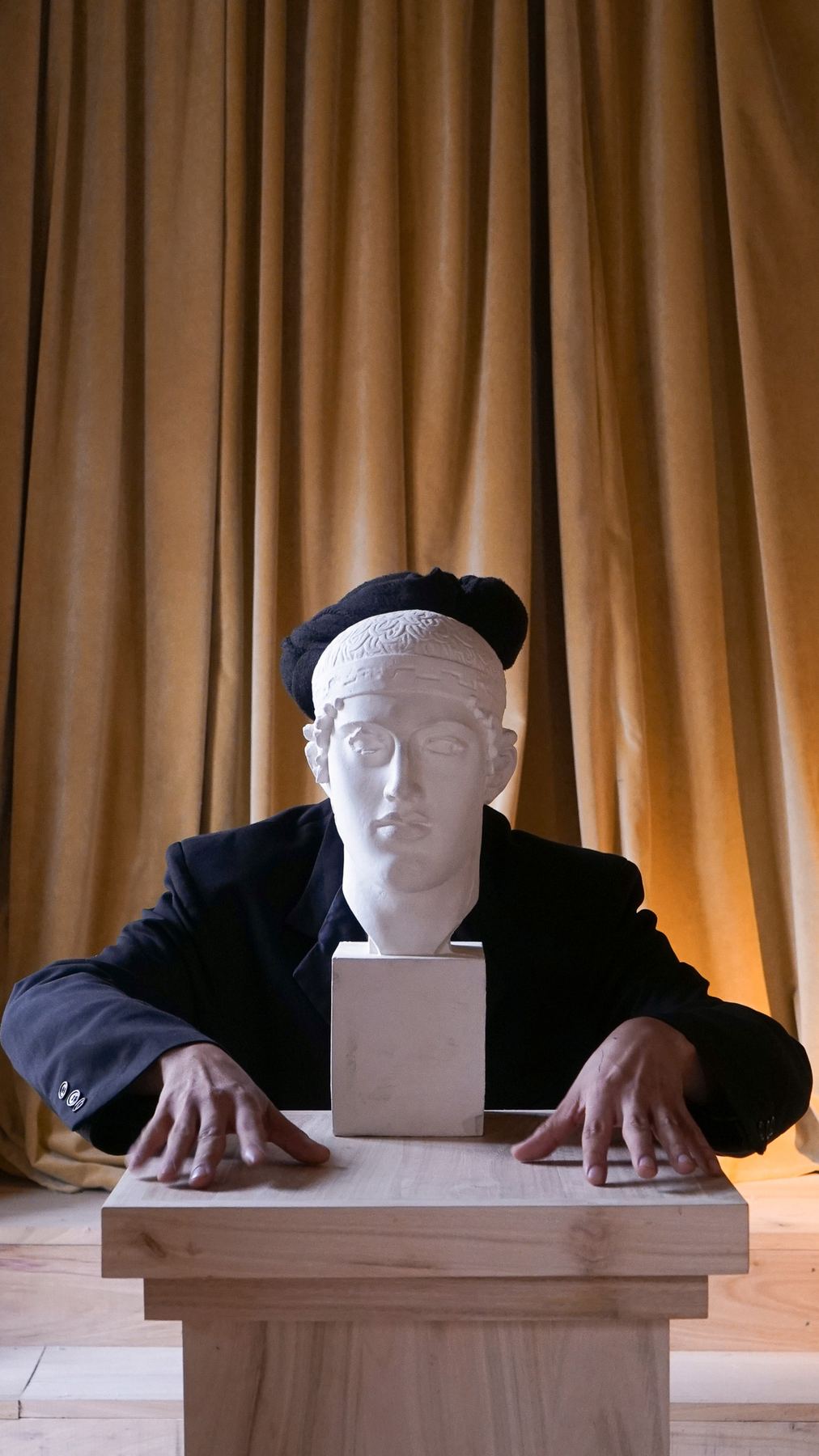 Uma figura com casaco preto e boina, por trás de um busto clássico de gesso, nas instalações do Palácio do Grilo em Lisboa.