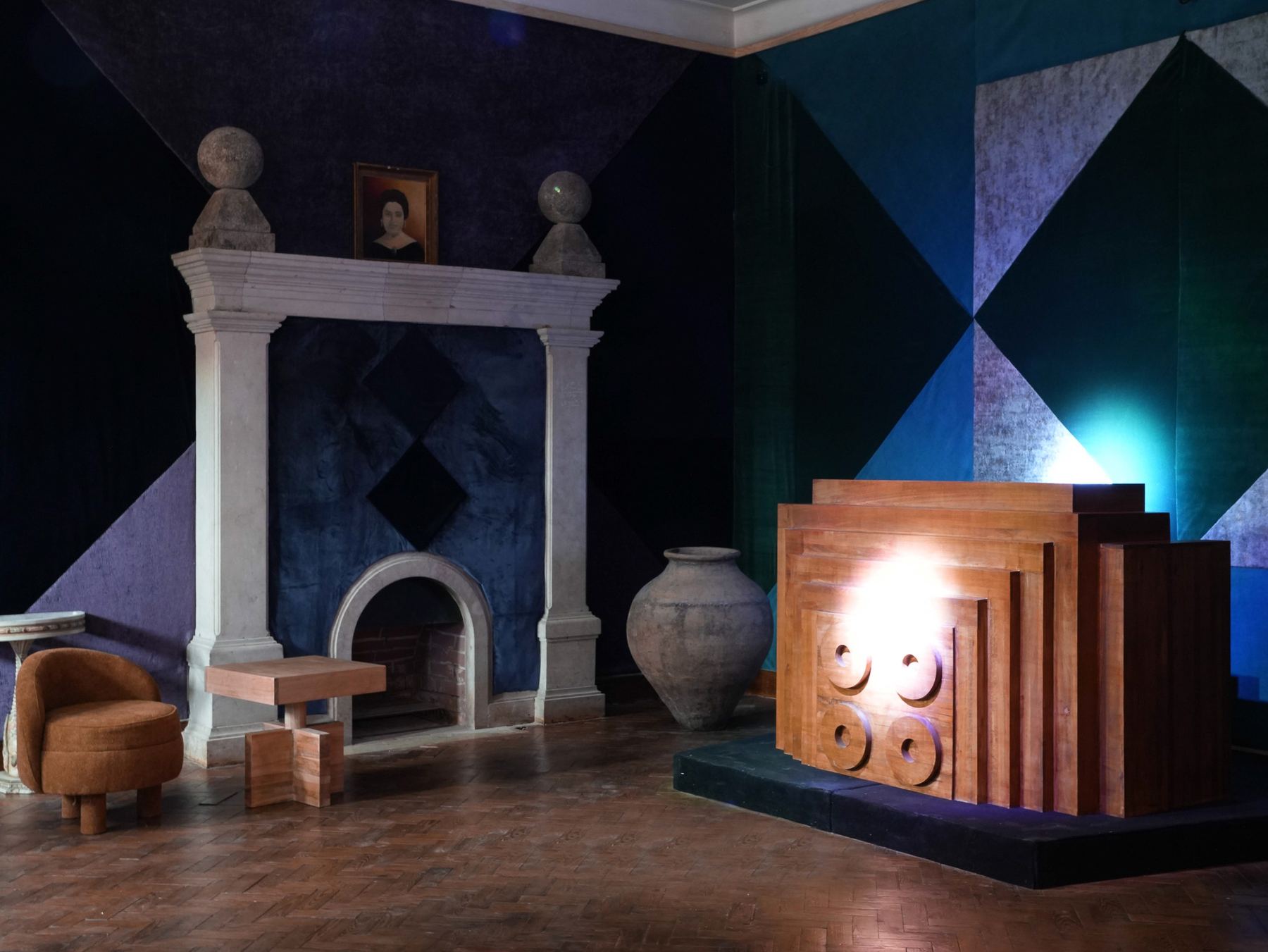 Uma sala do Palácio do Grilo, em Lisboa, apresenta uma lareira clássica e mobiliário moderno contra paredes geométricas.