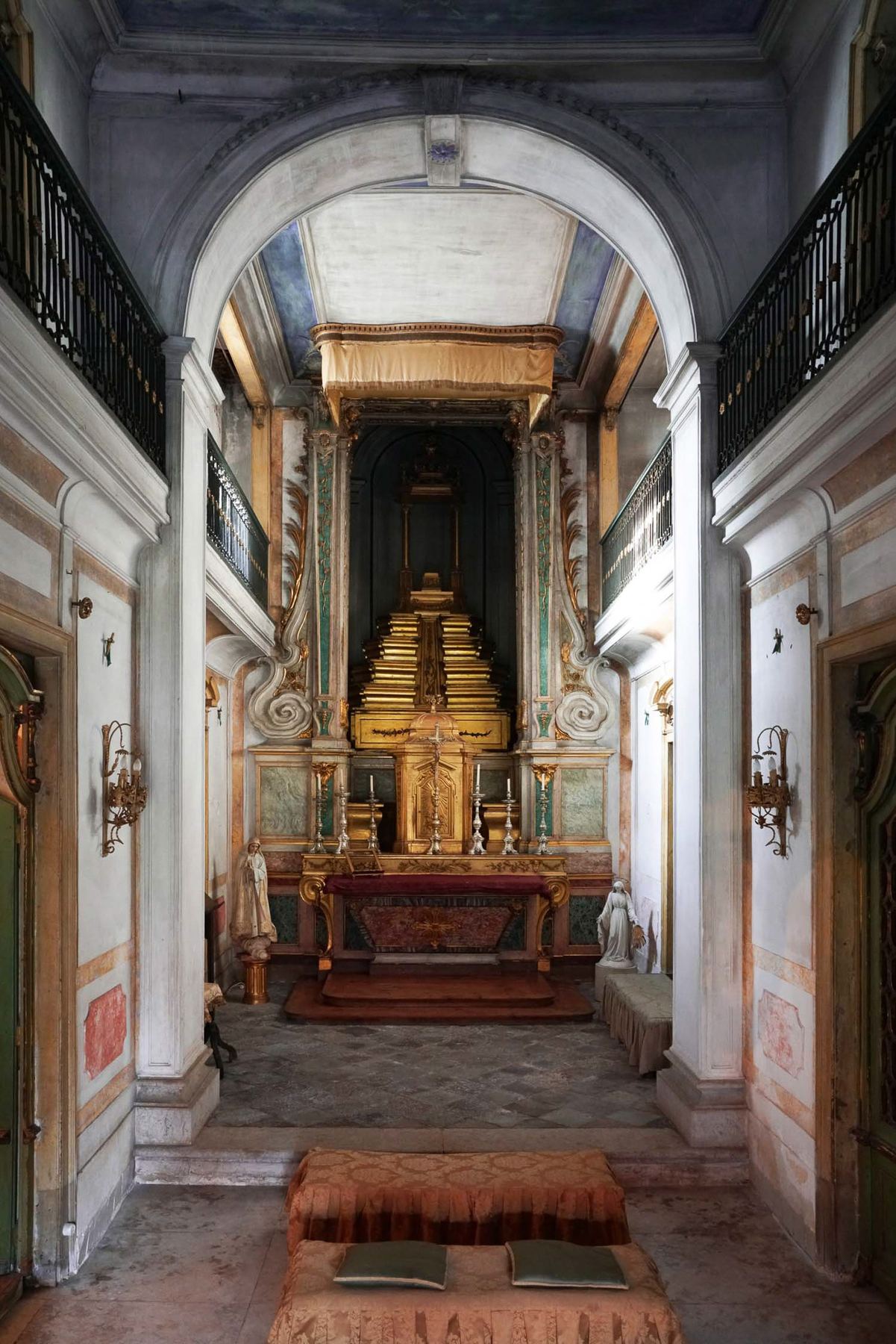 Capela barroca ornamentada com altar dourado e órgão, ladeada por varandas, em Palácio do Grilo, Lisboa.