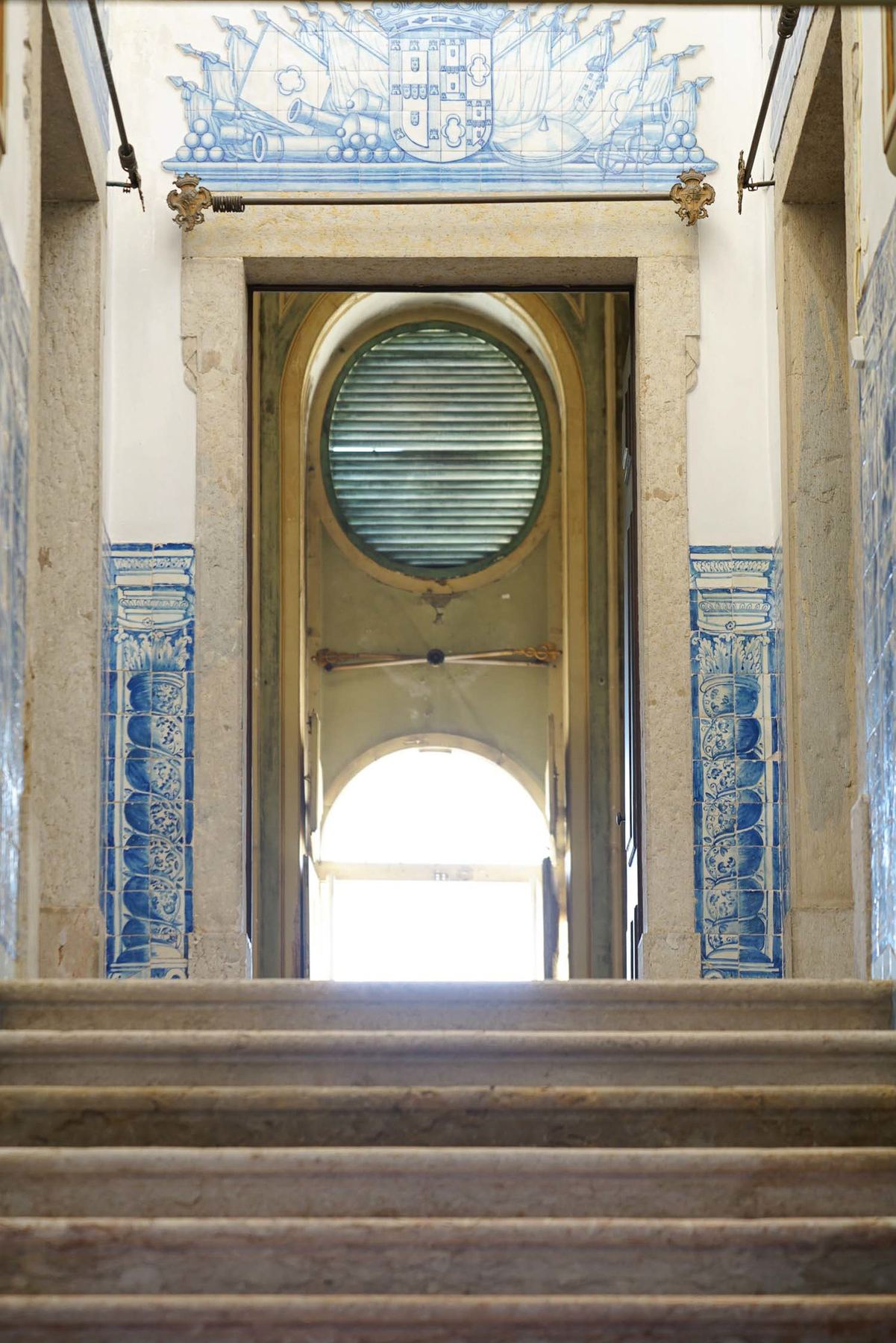 Escadaria de pedra do Palácio do Grilo com azulejos azuis e entrada iluminada, revelando a arte de Lisboa.