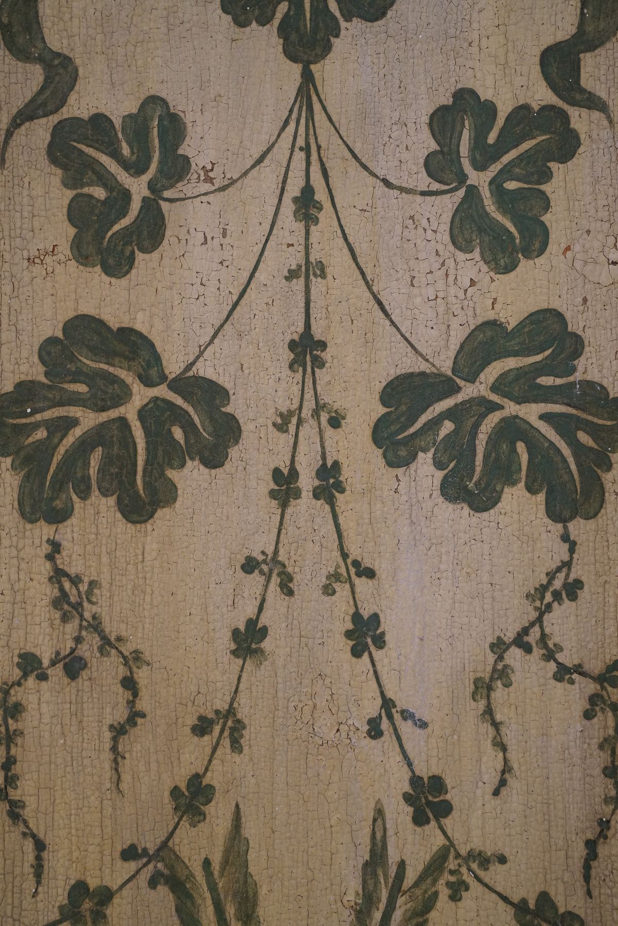 Close-up de um padrão floral verde pintado em parede envelhecida e rachada no Palácio do Grilo, Lisboa.