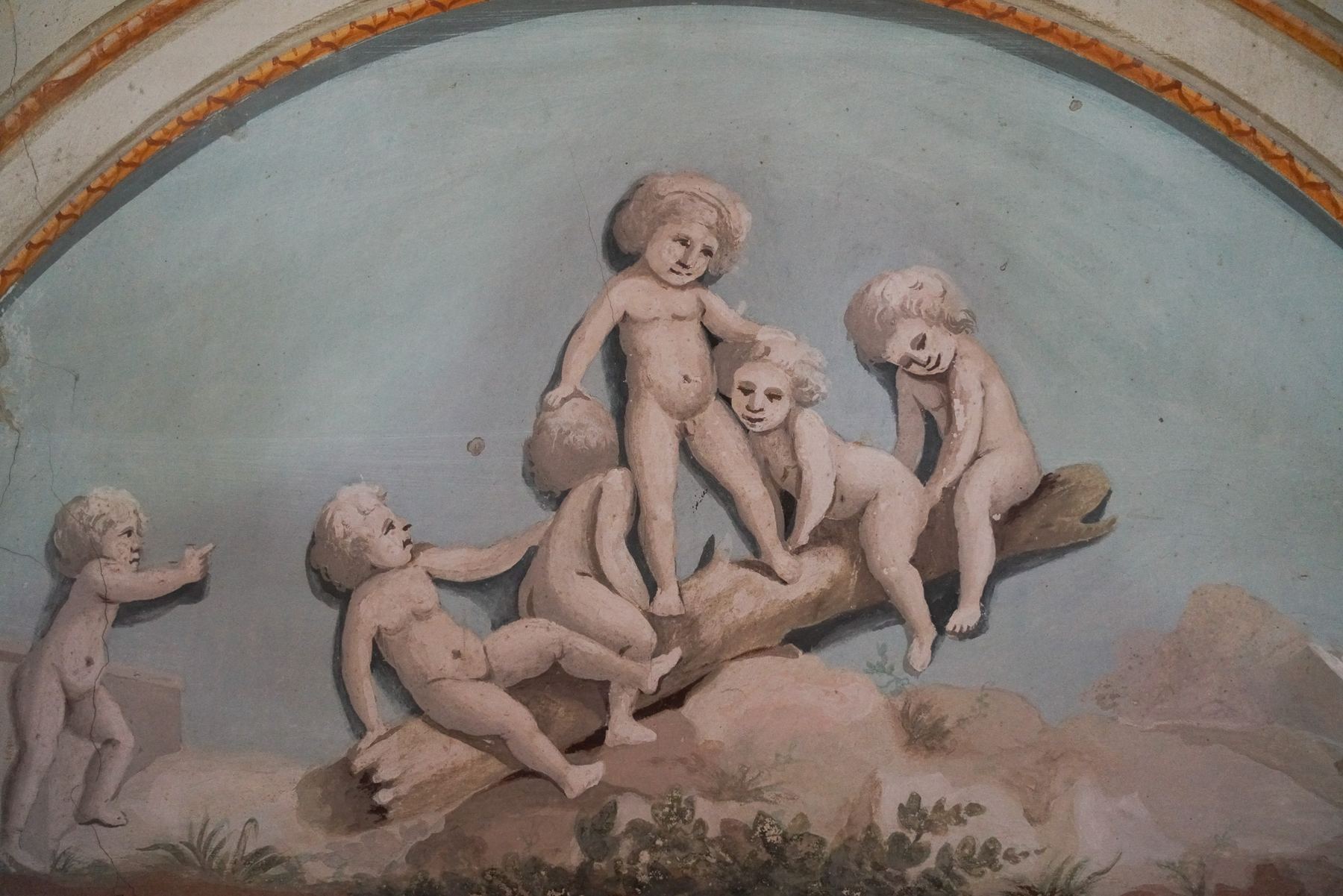 Detalle de fresco barroco no Palácio do Grilo, com putti rosados brincando sobre um tronco contra um céu azul em Lisboa.