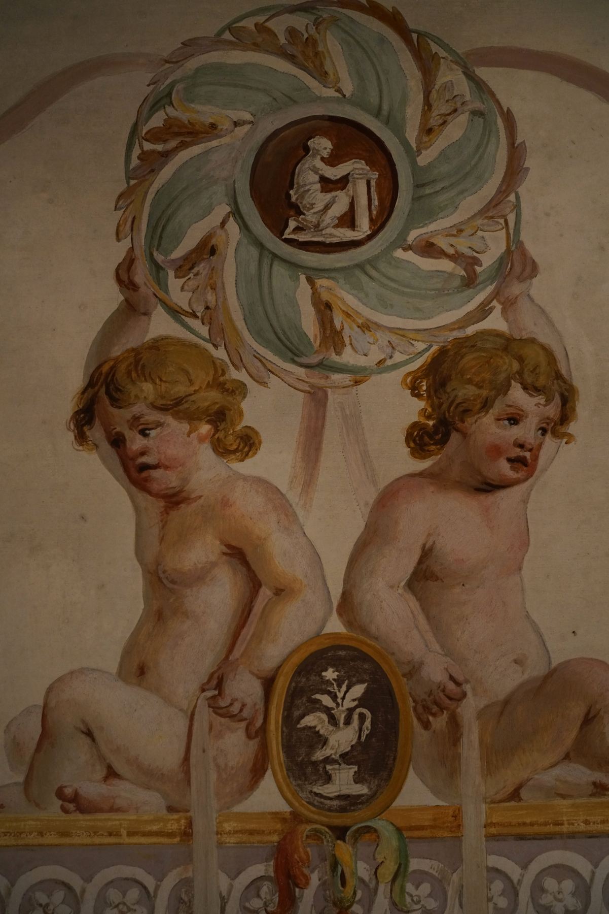 Fresco barroco no Palácio do Grilo, em Lisboa, representando dois putti observando um medalhão ornamentado com pássaro.