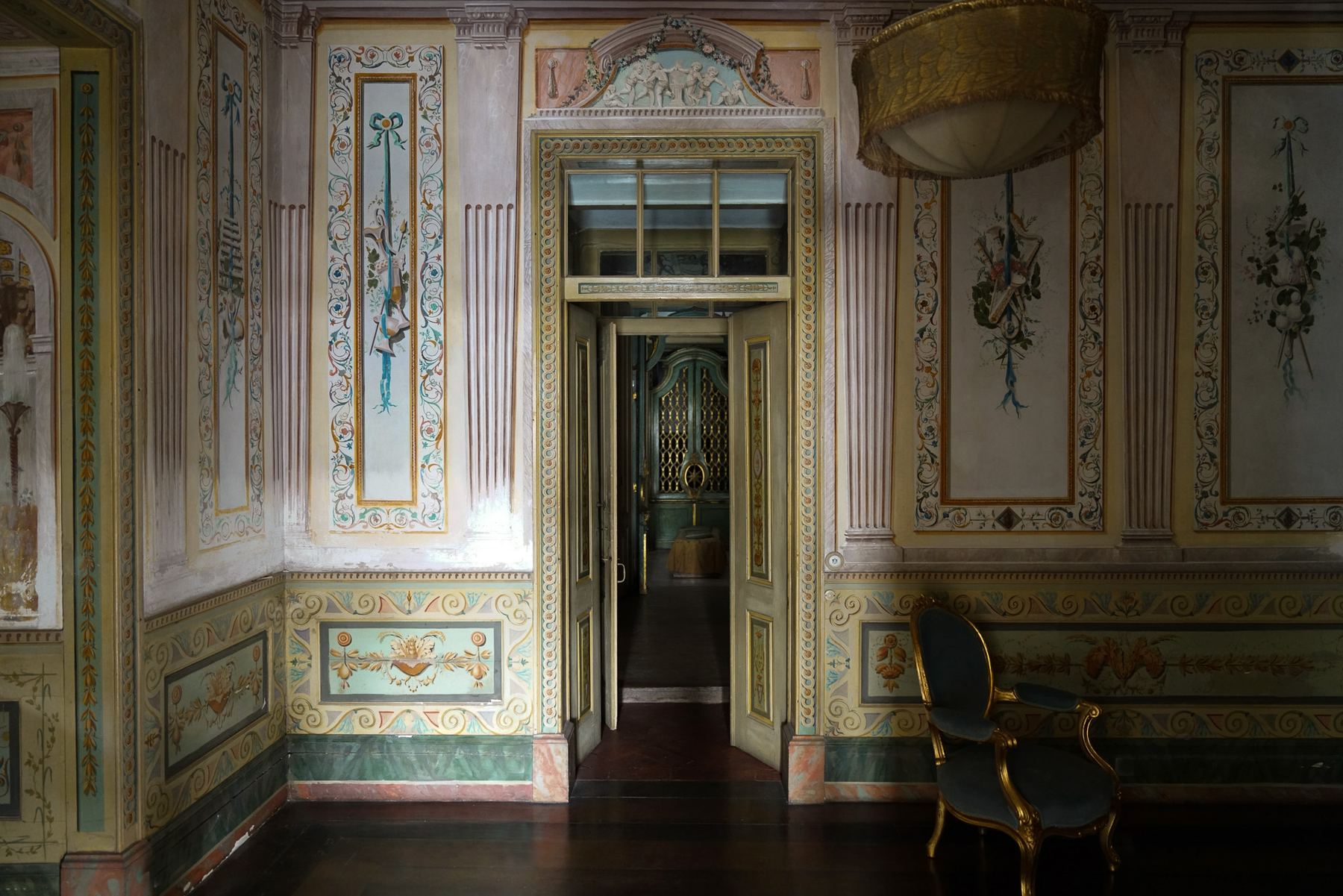Um salão ricamente decorado no Palácio do Grilo, Lisboa, com murais barrocos e uma poltrona, evocando o estilo de Palácio do Grilo.
