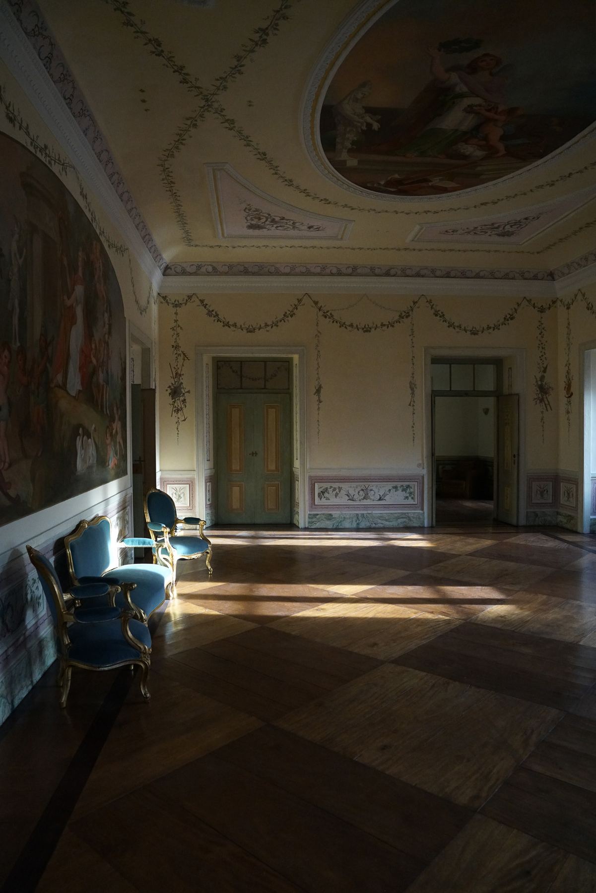 Um grandioso salão do Palácio do Grilo em Lisboa com luz solar filtrada, piso em parquet e mobiliário barroco azul.