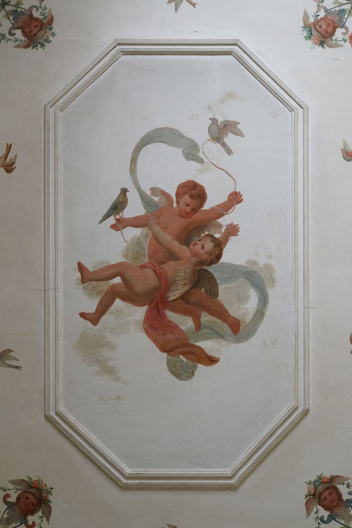 Teto do Palácio do Grilo em Lisboa com um fresco barroco de anjos e pássaros dentro de um medalhão octogonal.